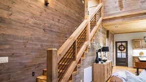 Eine Holztreppe führt zu einem Schlafzimmer auf dem Dachboden, mit Blick auf die Küche.