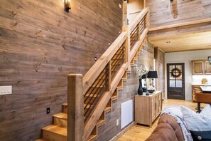 Eine Holztreppe führt zu einem Schlafzimmer auf dem Dachboden, mit Blick auf die Küche.