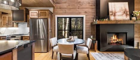 Cocina moderna con una isla grande, electrodomésticos de acero inoxidable y un comedor con una mesa redonda y sillas.