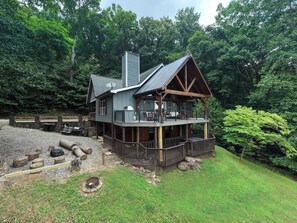 A two-story cabin with a deck, surrounded by a wooded area. - Bear Ridge-Private Cabin-Mountain Views-Hot Tub! (Blairsville)