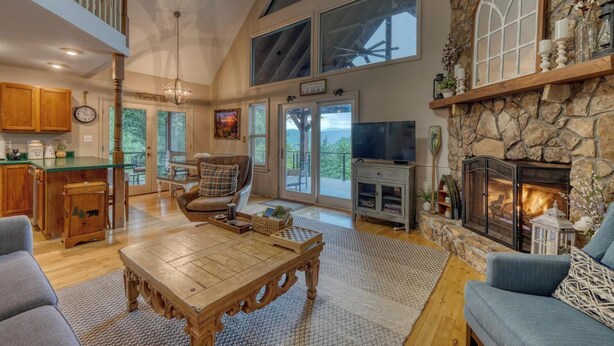 A spacious living room with a fireplace, a television, and a dining area with a view of the outdoors. - Bear Ridge-Private Cabin-Mountain Views-Hot Tub! (Blairsville)