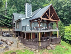 A two-story cabin with a balcony, surrounded by a forested landscape. - Bear Ridge-Private Cabin-Mountain Views-Hot Tub! (Blairsville)