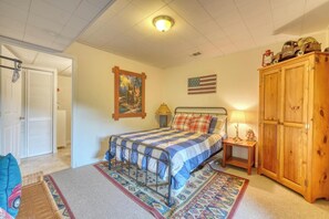 Une chambre à coucher avec un lit, une armoire en bois, un tapis et un tableau représentant un ours.