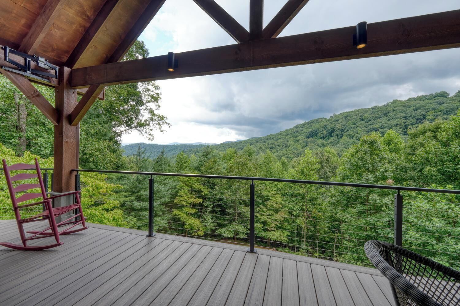 Une terrasse en bois offrant une vue sur une chaîne de montagnes boisées.