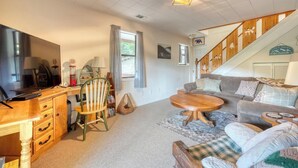 A cozy living room with a sofa, a coffee table, a TV, and a wooden desk with drawers. - Bear Ridge-Private Cabin-Mountain Views-Hot Tub! (Blairsville)