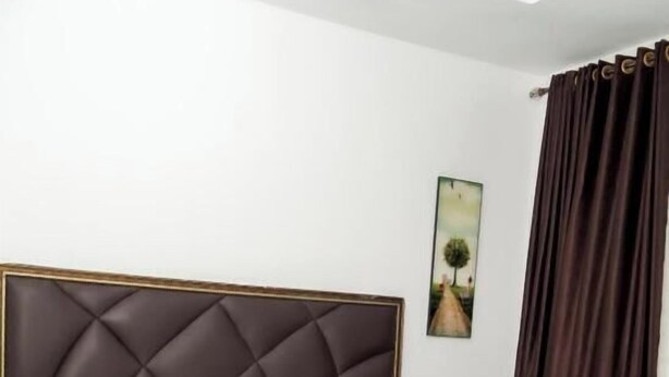 Una cama bien hecha con cabecera, almohada blanca y manta blanca.