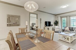 Ein modernes Wohnzimmer mit Essbereich, einer Chandelierleuchtre und einem großen Spiegel.
