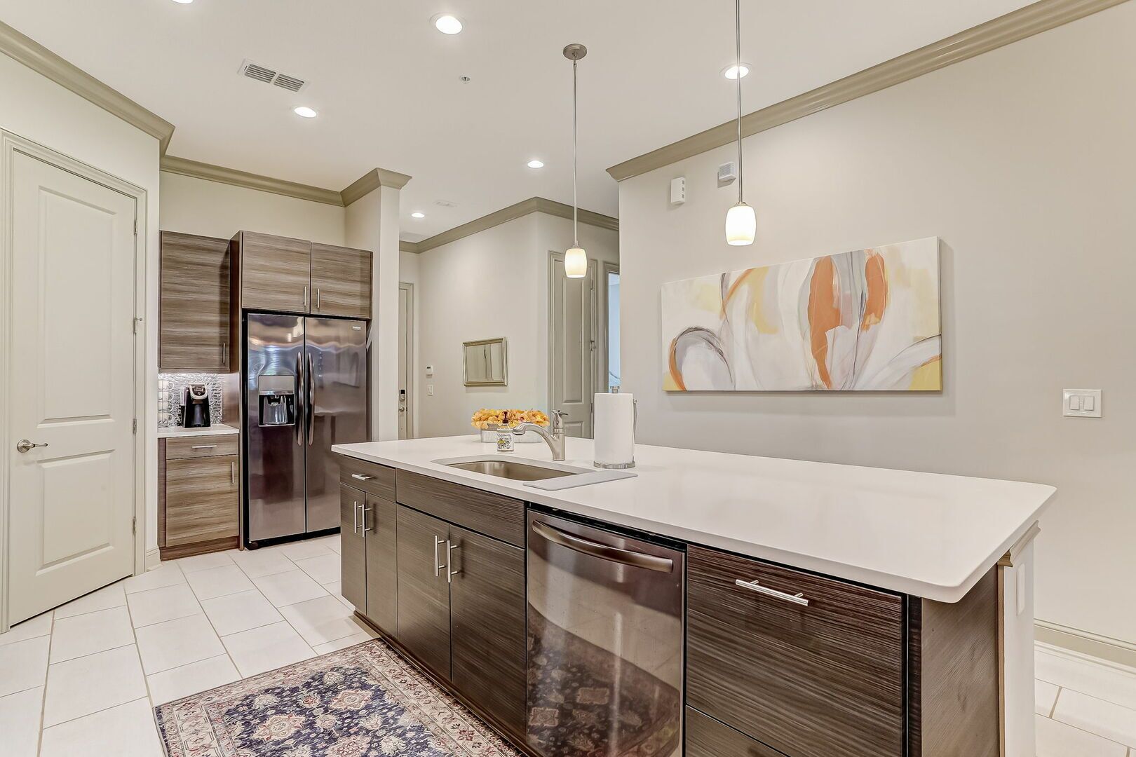 A modern kitchen with a central island, stainless steel appliances, and a large mirror.