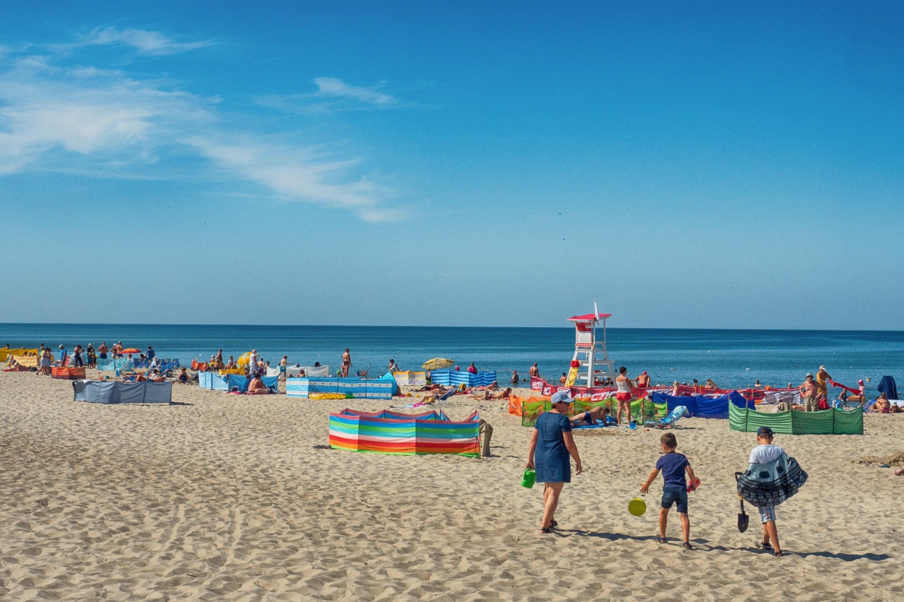A beach with people, umbrellas, and a lifeguard tower.