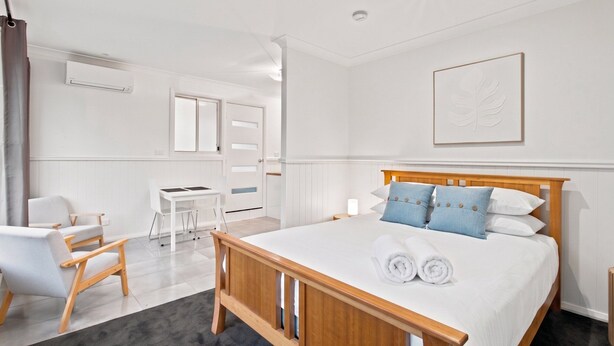 Een hotelkamer met een houten bed, een bureau, een stoel en een groot raam.