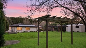 Een woonhuis met een overdekte patio, een woning en een tuinhuis.