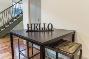 Ein dunkles Holztisch mit Metallgestell und daran befestigter Bank. Auf dem Tisch befindet sich ein Metallschild mit dem Wort 'HELLO' in Großbuchstaben.