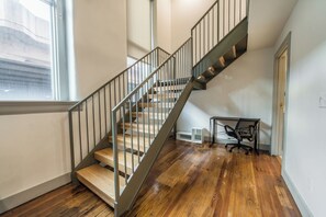 Eine Treppe mit Holzbodenstufen und Metallgeländern, die zu einer Zwischenebene mit Schreibtisch und Stuhl führt.
