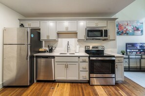 A modern kitchen with stainless steel appliances, white cabinetry, and a wooden floor. - Spacious Loft - Parking Nearby - DT - 2F (Louisville)