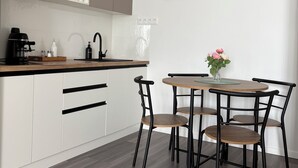 Une cuisine moderne avec des meubles blancs, un plan de travail en bois et un coin repas comprenant une table et des chaises.