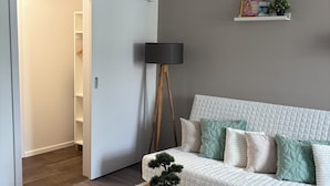 Un salon moderne avec un canapé blanc, une table basse, un lampadaire et une bibliothèque.