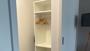 Un dressing accessible sans porte, avec des cintres en bois et un lampadaire.