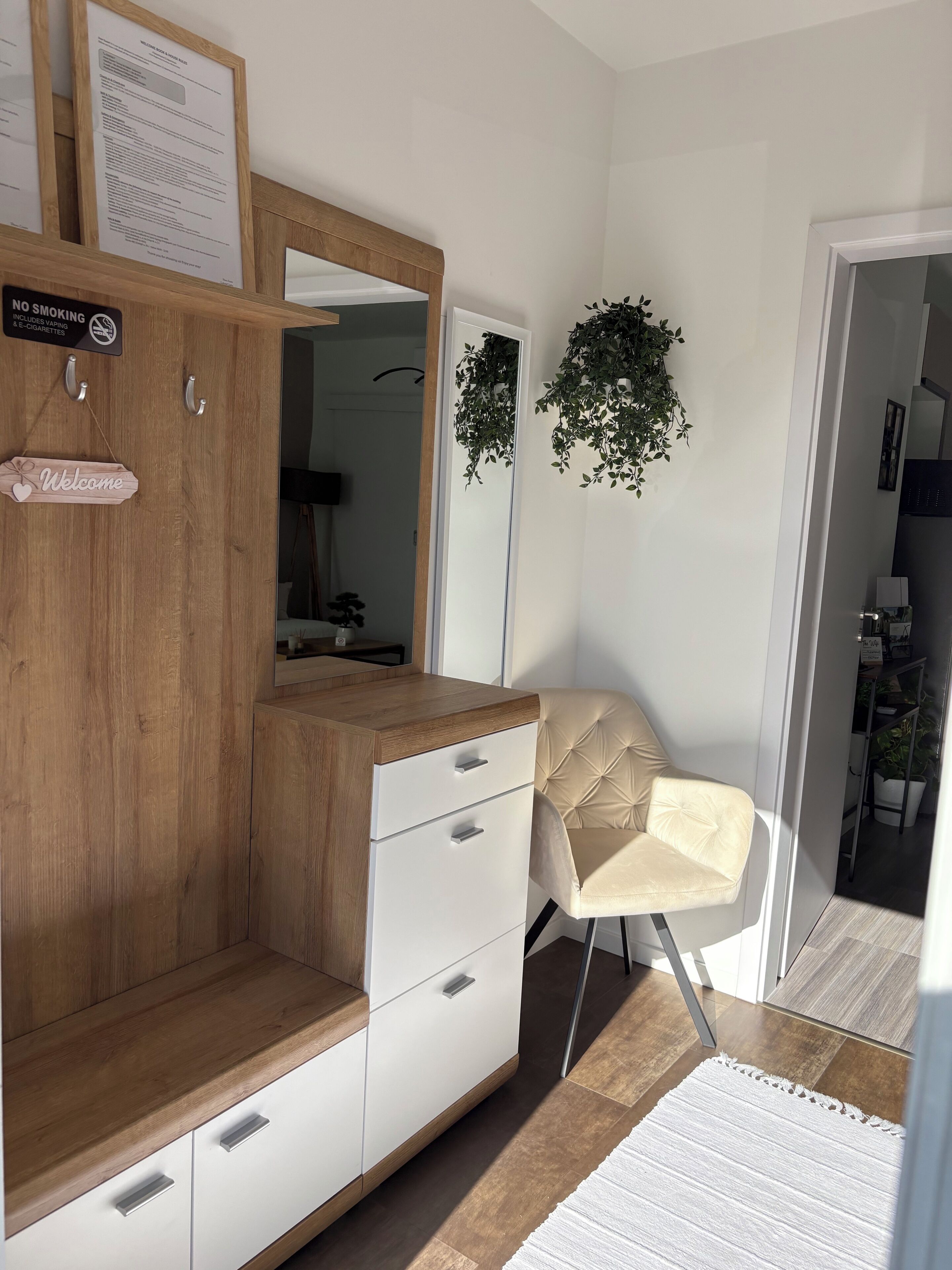 Une chambre moderne avec une armoire en bois, un fauteuil beige et un miroir.