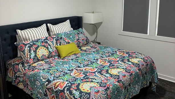 A bedroom with a bed, a ceiling fan, a window, and a nightstand. - Two bedroom underground space sits right on the water. (Eclectic)