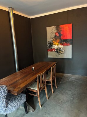 A dining area with a wooden table, two chairs, and a single candle. - Two bedroom underground space sits right on the water. (Eclectic)