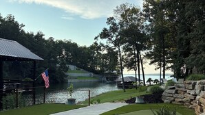 A landscaped area with a view of a body of water, a flag, and a gazebo. - Two bedroom underground space sits right on the water. (Eclectic)