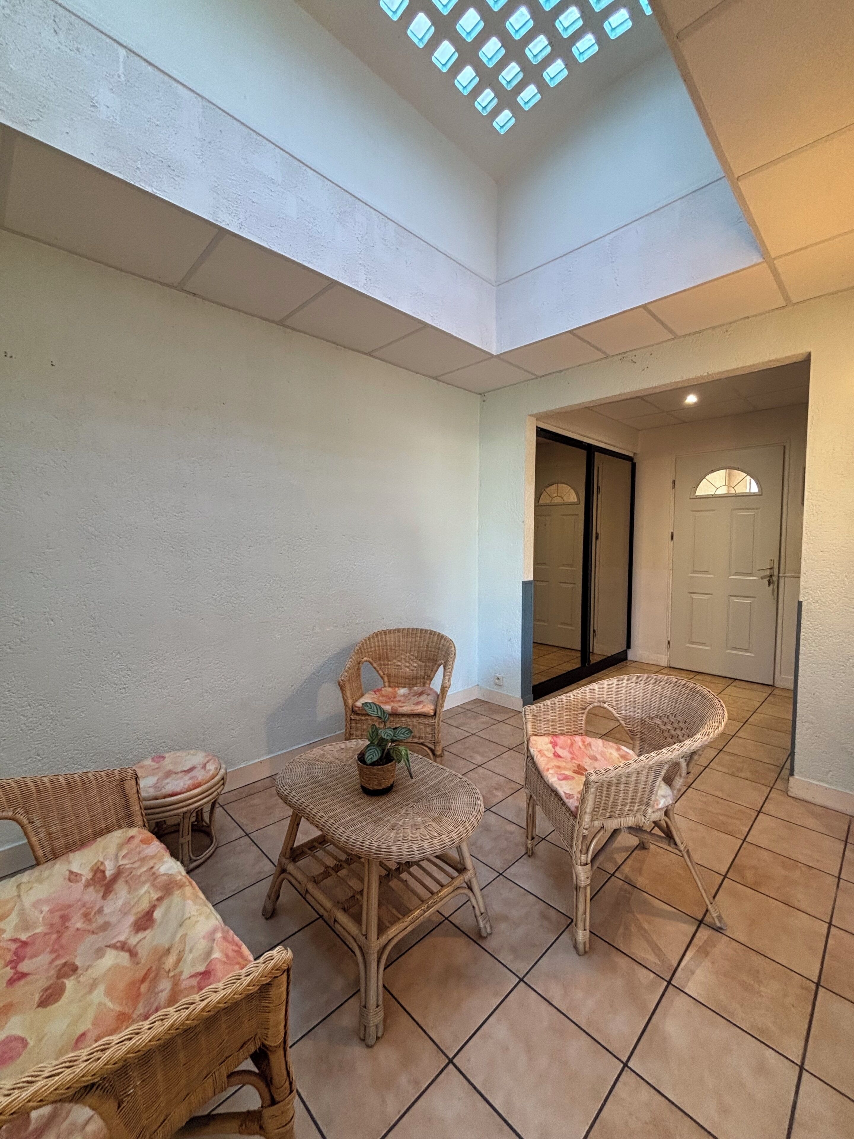 A sunlit patio with wicker furniture and a tiled floor.