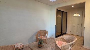 A sunlit patio with wicker furniture and a tiled floor.