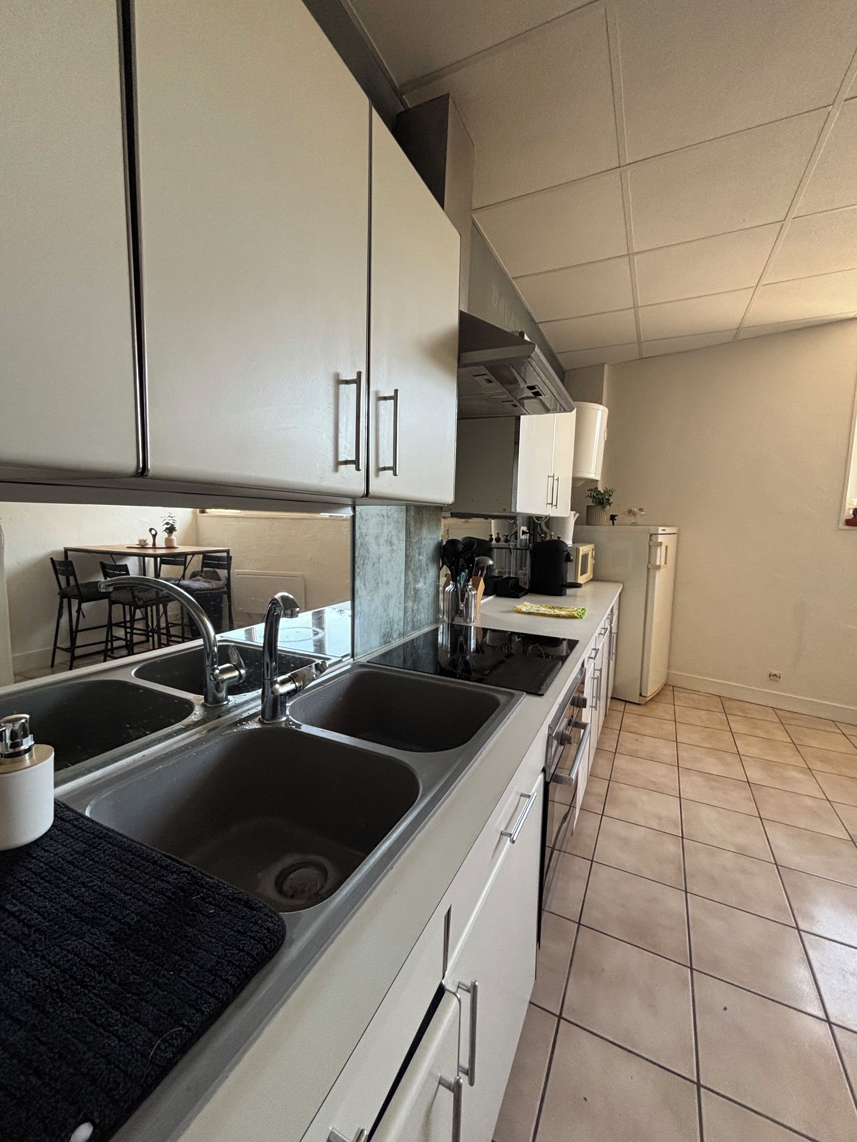 Una cocina moderna con un lavamanos doble, electrodomésticos de acero inoxidable y piso de baldosas.