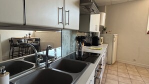 A modern kitchen with a double sink, stainless steel appliances, and a tiled floor.