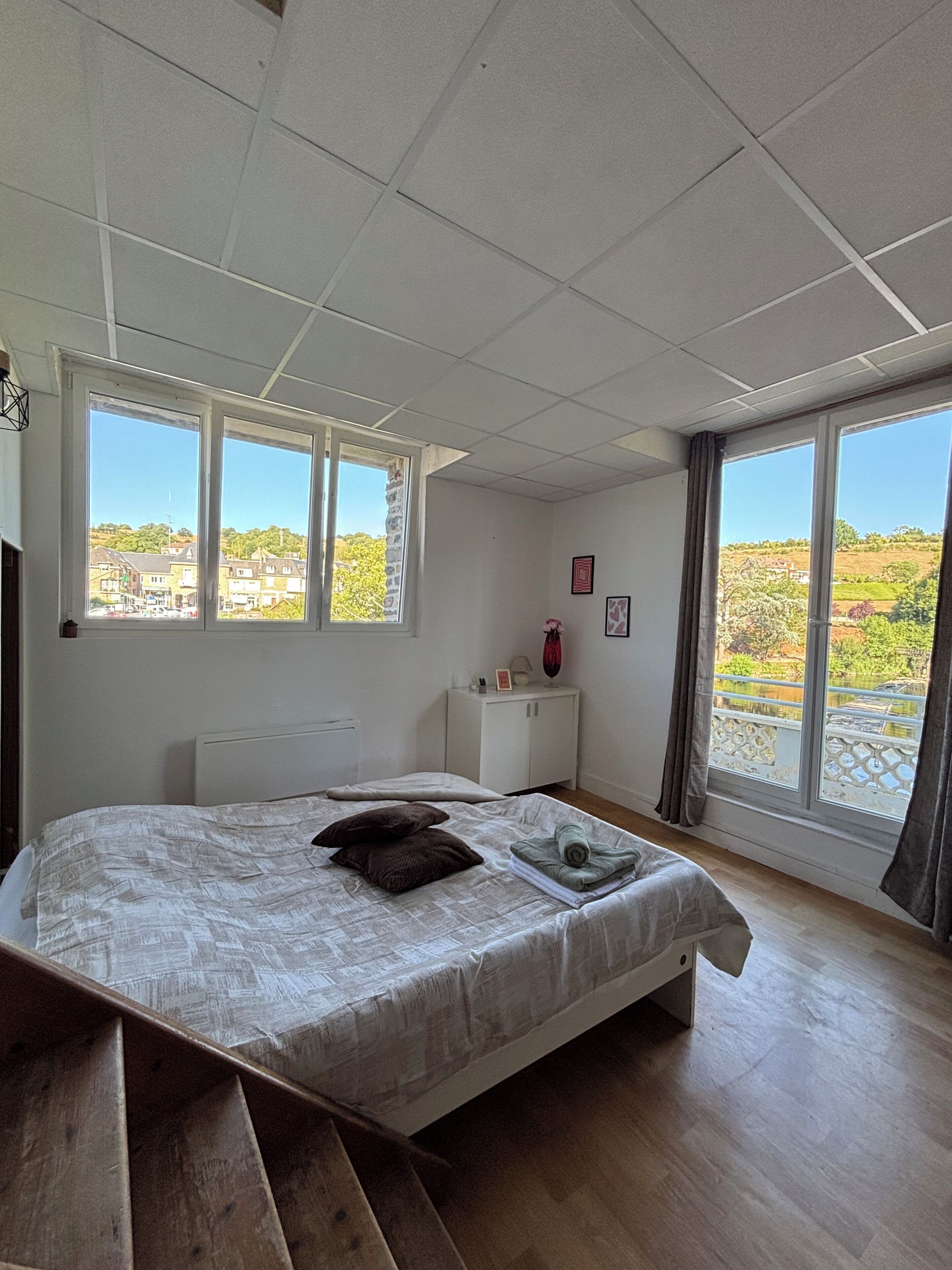 Une chambre à coucher avec un lit, une table de chevet, une fenêtre et une vue sur l’extérieur.