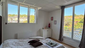 Une chambre à coucher avec un lit, une table de chevet, une fenêtre et une vue sur l’extérieur.