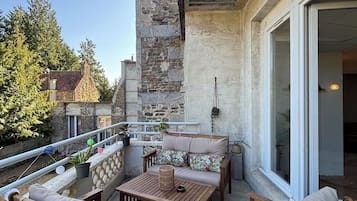 Un espace extérieur abrité, aménagé avec du mobilier en bois et doté d’un mur en pierre.