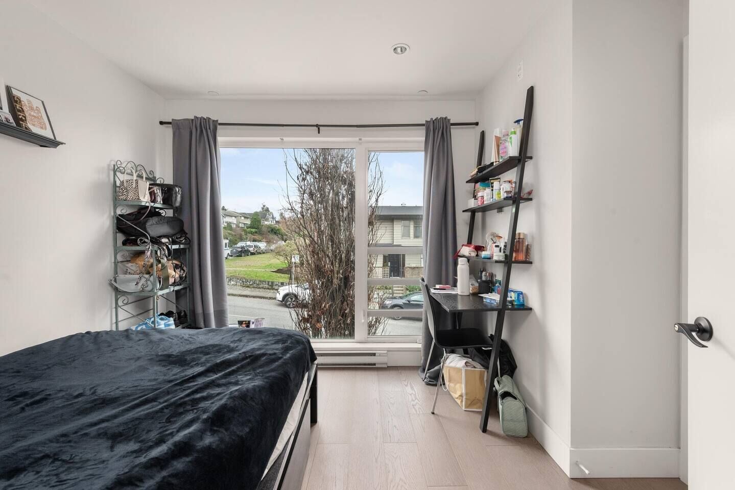 Ein Schlafzimmer mit einem Bett, einem Schreibtisch und einem Fenster mit Blick nach draußen.
