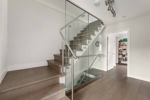 A modern staircase with glass railings and wooden steps. - Elite Townhouse @ the Shipyards (North Vancouver)