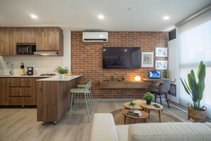Eine moderne Küche mit integriertem Mikrowellenofen, einem Essbereich mit Sofa und Sesseln sowie einem an einer Ziegelwand befestigten Fernseher.