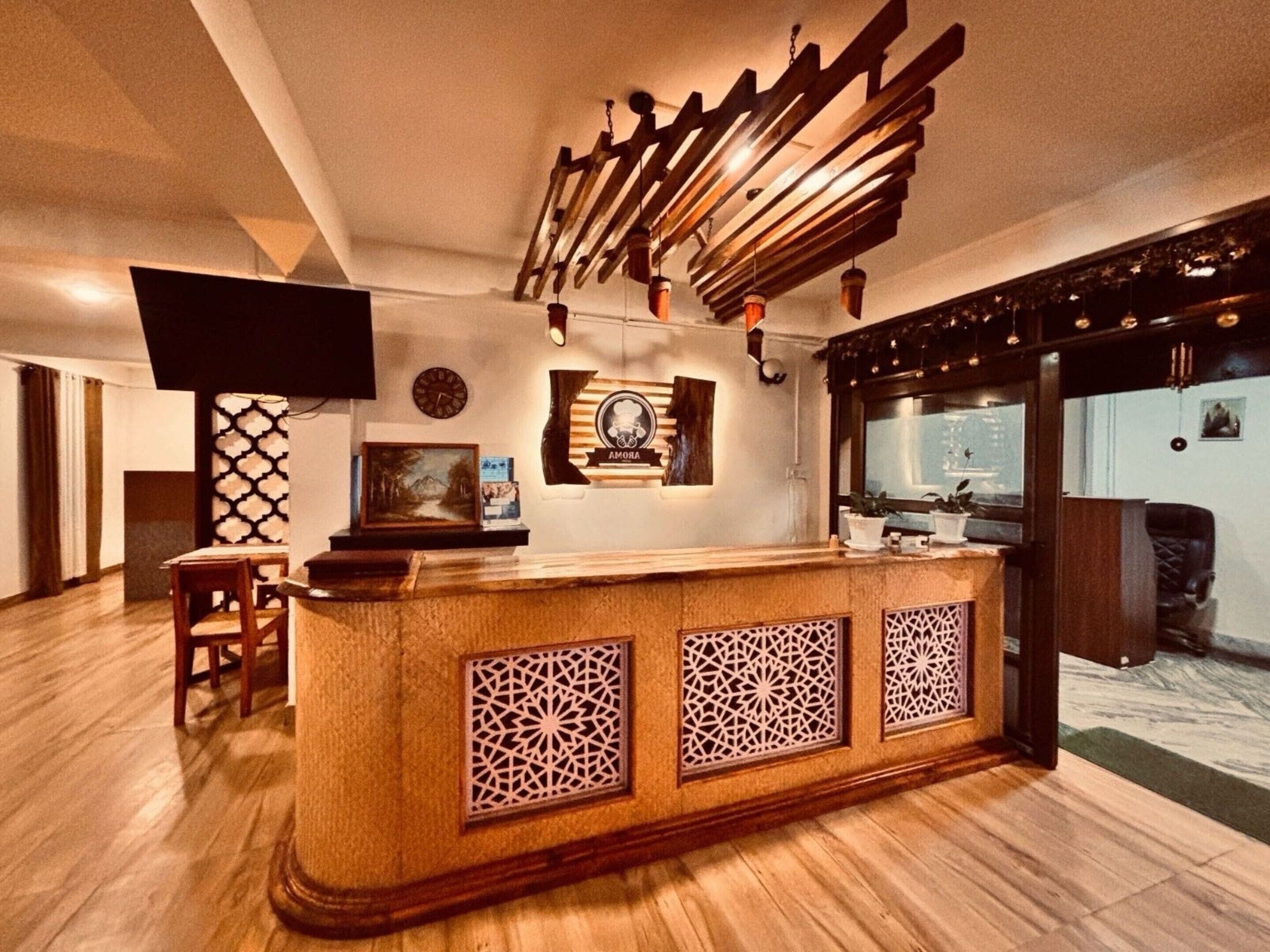 A reception area with a wooden reception desk, a flat-screen TV, and a wall-mounted clock.