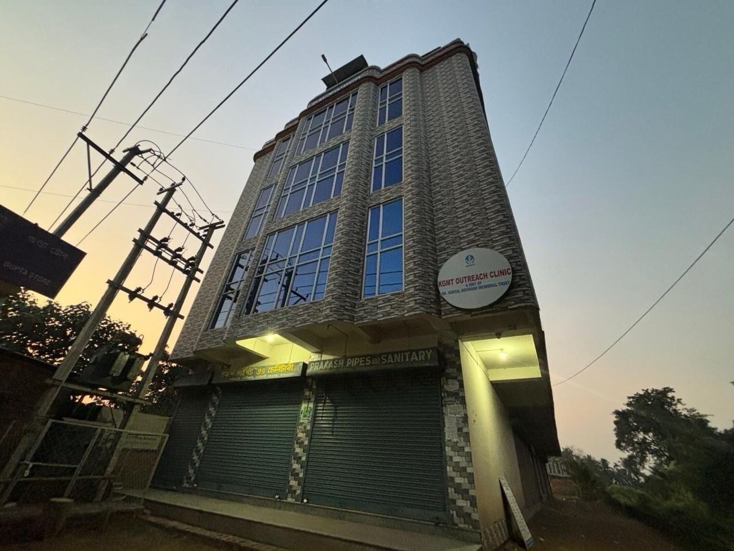 Un edificio de varios pisos con fachada de piedra, un letrero de la Clínica de Extensión KGMC y una tienda cerrada en la planta baja.