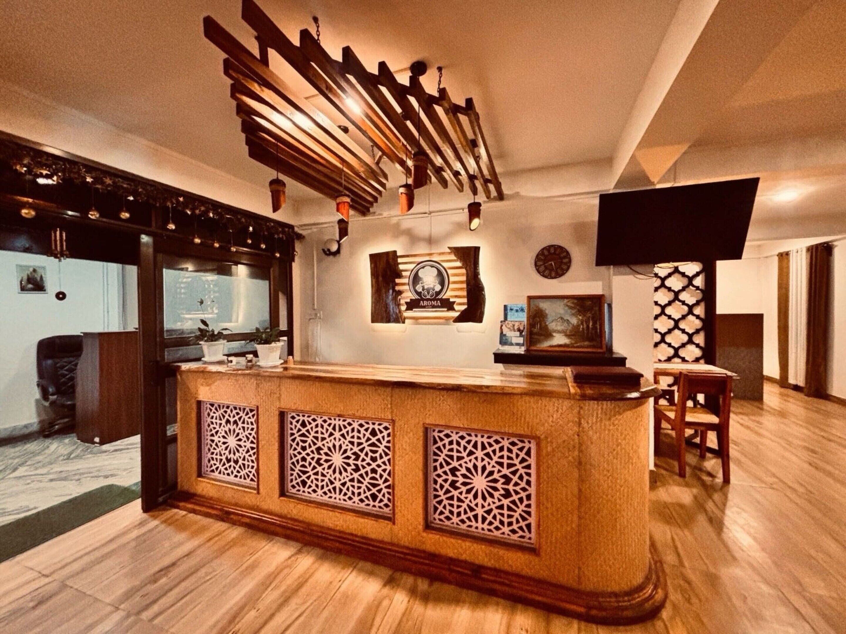 Un área de recepción con mostrador de madera, paneles decorativos, un reloj y una televisión.