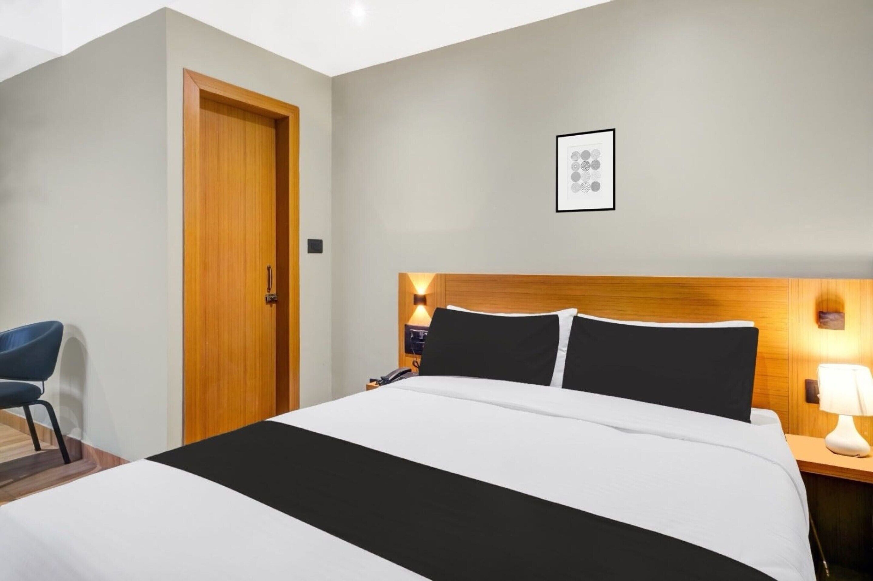 Una camera d'albergo con un letto, una scrivania, una sedia, una porta e un quadro appeso al muro.