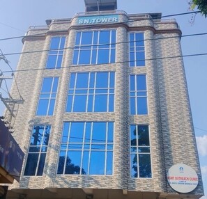 A building with a sign reading 'SN.TOWER' and another sign for 'KGMT Outreach Clinic'. - Hotel O Kahilipara Nirvis Grand (Guwahati)
