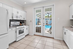 A kitchen with white cabinets, a stove, and a microwave. - Blue Chip Escape-Private Pool-30A-Bikes (Santa Rosa Beach)