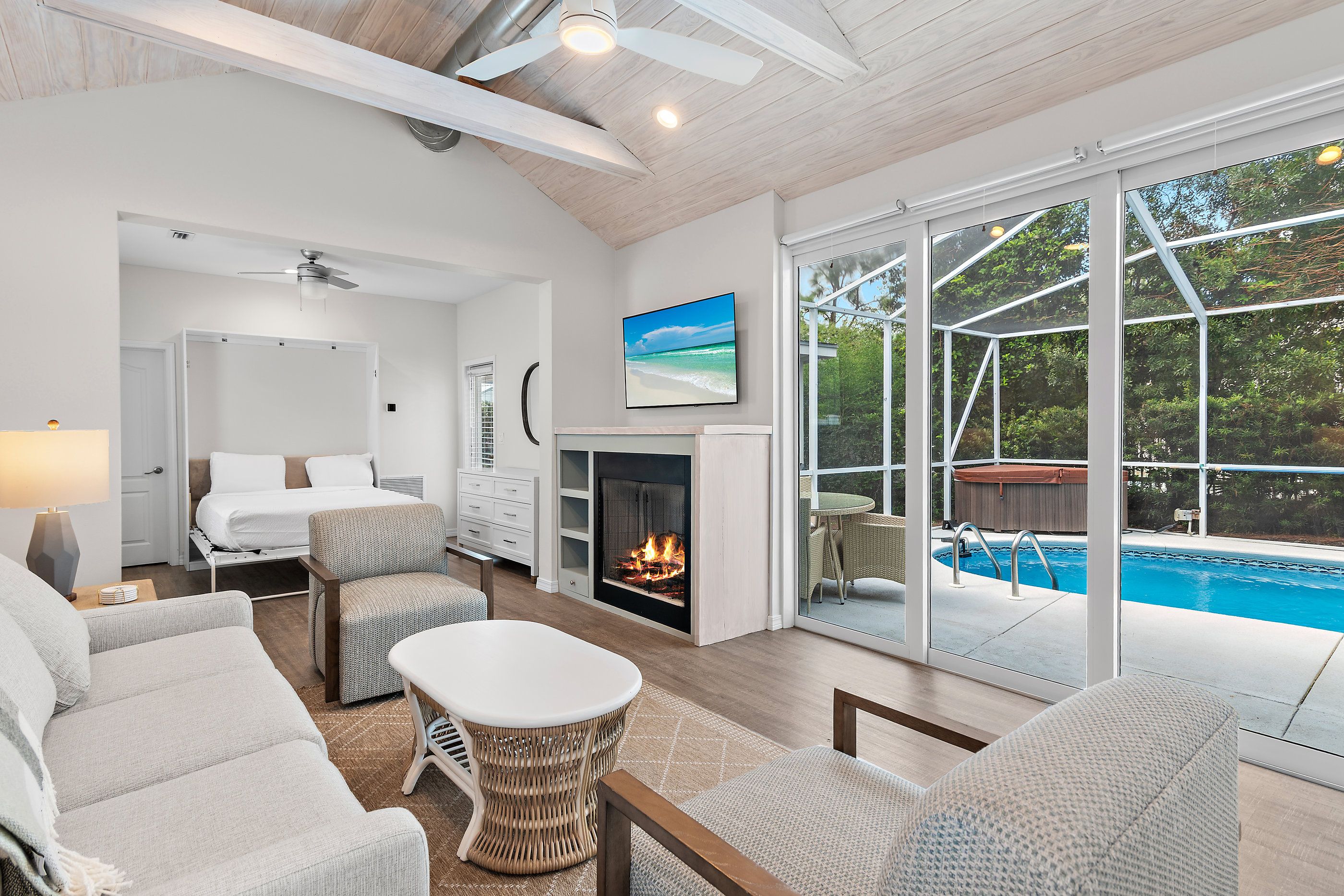 A spacious living room with a fireplace, comfortable seating, and a large window overlooking a pool.