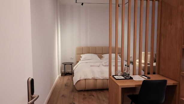 Un dormitorio moderno con cama, mesita de noche y escritorio con silla.