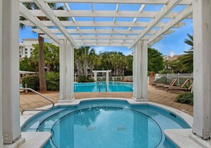Ein Poolbereich mit Pergola, umgeben von Palmen und einem eingezäunten Poolufer.