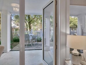 A room with a sliding glass door leading to an outdoor patio area with a table and chairs. - 🏖️ Sandestin Retreat | 1BR pool level condo | hot tub | Baytowne 🐬 (Miramar Beach)