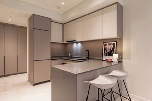 A modern kitchen with a central island, bar stools, and a poster on the wall. - The Opera D2 Apartment  (Ho Chi Minh City)