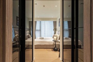A modern hotel room with a large bed, bedside tables, and a view through a glass door. - The Opera D2 Apartment  (Ho Chi Minh City)