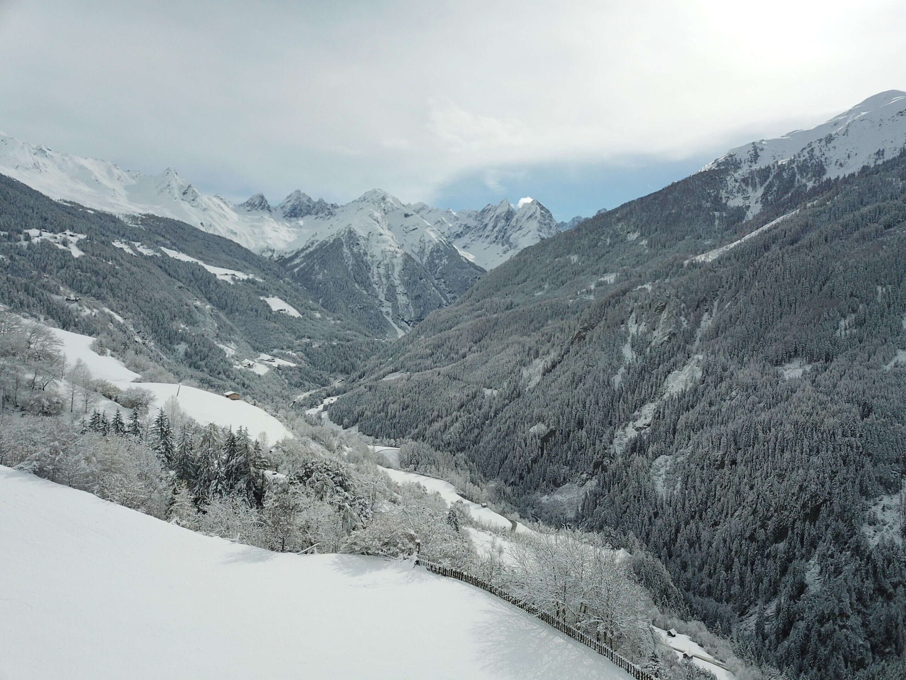 A mountainous landscape with snow-covered slopes and dense forests.