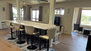 Uma cozinha moderna com uma ilha central, banquetas, televisão e uma área de jantar com vista.