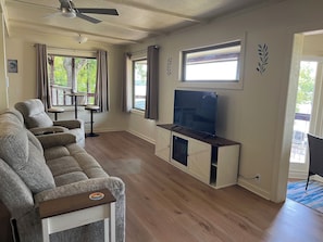Una sala de estar con sofá, televisor y ventanas.